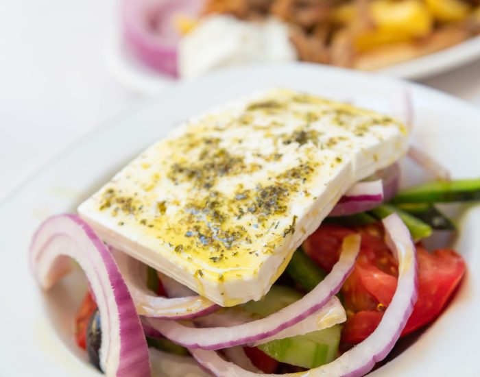 Traditional Greek Salad served in tavern, traditional greece food. Feta cheese, tomatoes, cucumber, onions, olives, peppers, cappers and olive oil